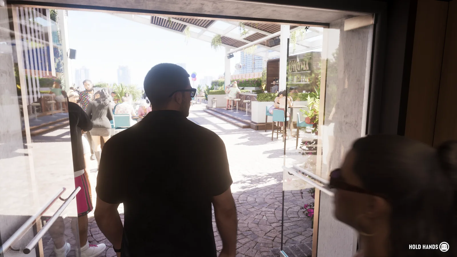 Jason walking with Lucia onto a sunlit rooftop bar terrace in GTA 6, with a Hold Hands prompt on screen